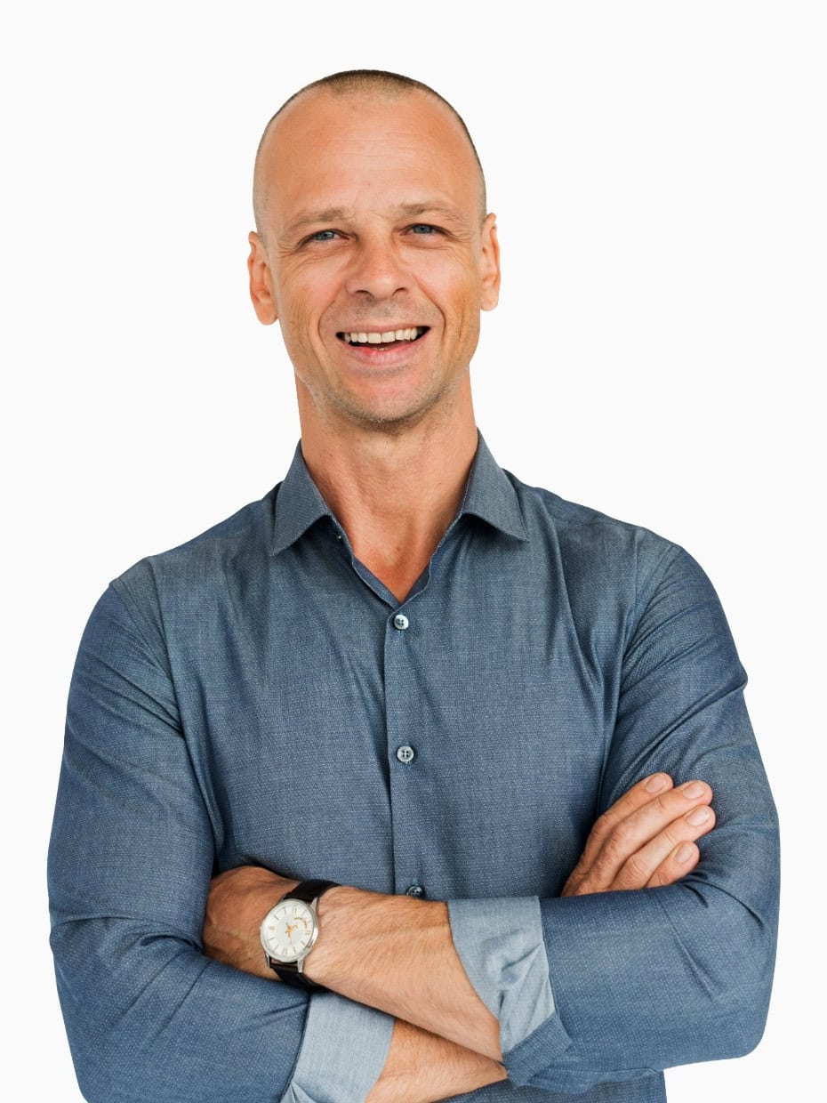 Smiling man wearing a blue shirt with arms crossed against a plain background.